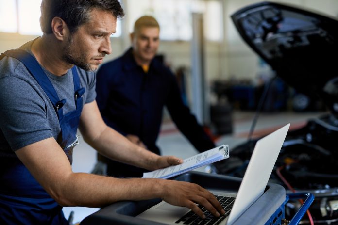 Mid adult mechanic using laptop for car diagnostic in auto repai